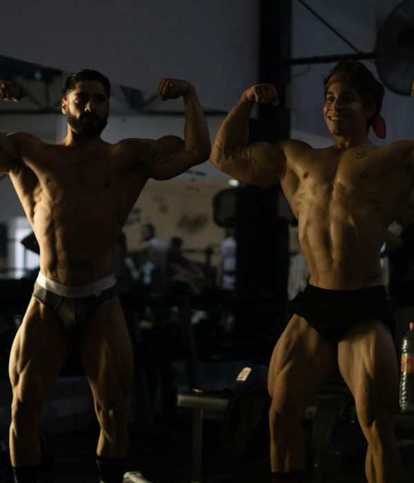 Man performing a strength exercise in a dark gym with ruby light.