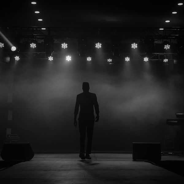 Silhouette of a man stretching against a dark, minimalist background.